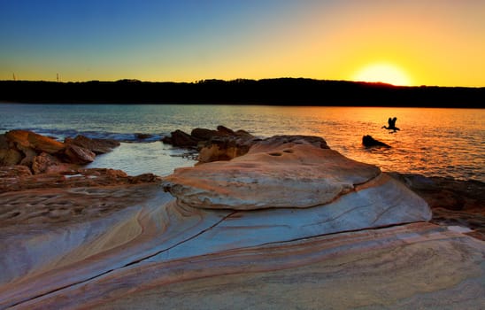 Looking at the sunrise from Bare Island, La Perouse, Sydney Australia. Beautiful sandstone rocks in the foreground.  Bracketed exposure with filter.