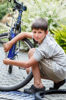 Teenager repairing his bike, using spanner to change broken tyre, outdoor shoot