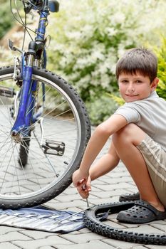 Teenager repairing his bike, using spanner to change broken tyre, outdoor shoot