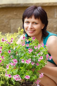 happy smiling middle age woman gardening, offsets the flowers in a pot