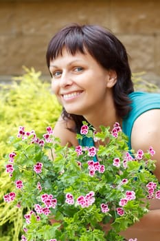 happy smiling middle age woman gardening, offsets the flowers in a pot
