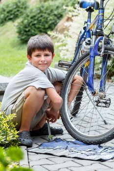 Teenager repairing his bike, using spanner to change broken tyre, outdoor shoot