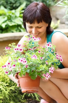happy smiling middle age woman gardening, offsets the flowers in a pot