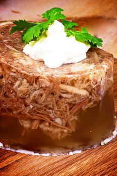 Delicious Aspic with Boiled Beef and Pork, Garlic and Spices Garnished with Horseradish closeup on Wooden Cutting Board