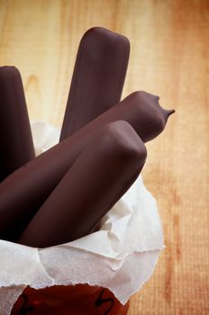 Bunch of Ice Cream Sticks Glazed in Dark Chocolate on Rustic Wooden background