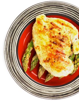 Delicious Roasted Chicken Breast with Asparagus Sprouts on Red Striped Plate closeup on white background. Top View
