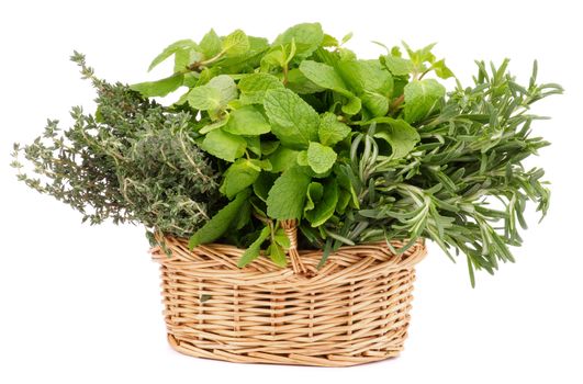Bunch of Fresh Rosemary, Mint and Thyme in Wicker Basket isolated on white background