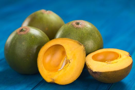 Peruvian fruit called Lucuma (lat. Pouteria lucuma) which has a dry, sweet flesh, and is mostly used to prepare juices, milkshakes, yogurts, ice cream and other desserts (Selective Focus, Focus on the standing lucuma half) 