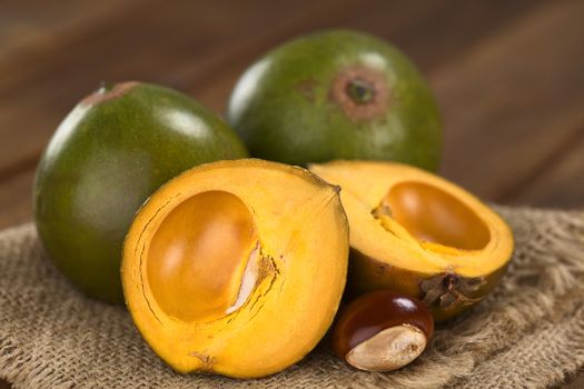 Peruvian fruit called Lucuma (lat. Pouteria lucuma) which has a dry, sweet flesh, and is mostly used to prepare juices, milkshakes, yogurts, ice cream and other desserts (Selective Focus, Focus on the standing lucuma half) 