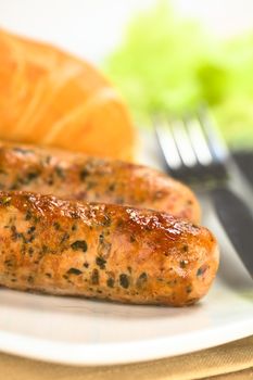 Fried bratwurst with bun, traditional German fast food served on plate (Selective Focus, Focus on the front of the first bratwurst)