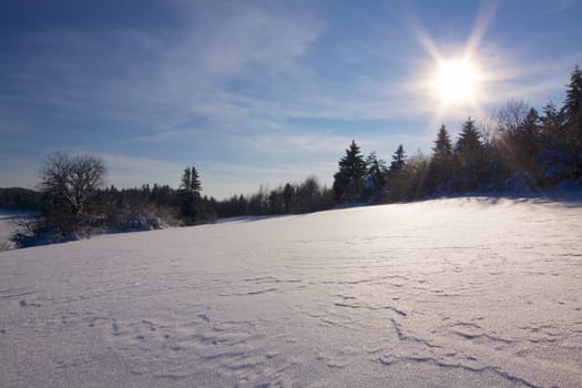 Picturesque snowy winter panorama with sun and blue sky