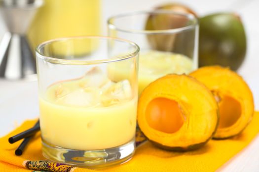 Peruvian cream liqueur made of lucuma fruit served in glass with ice cubes (Selective Focus, Focus on the front of the glass rim)