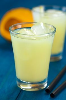 Peruvian cream liqueur made of lucuma fruit served in glass with ice cubes (Selective Focus, Focus on the front of the ice cubes)