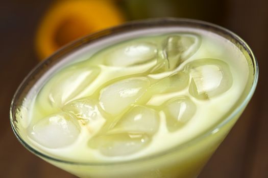 Peruvian cream liqueur made of lucuma fruit served in cocktail glass with ice cubes (Selective Focus, Focus in the middle of the ice cubes)