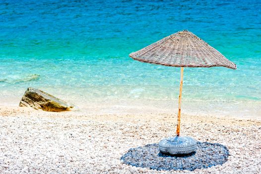 wicker parasol on the beach at the water's edge