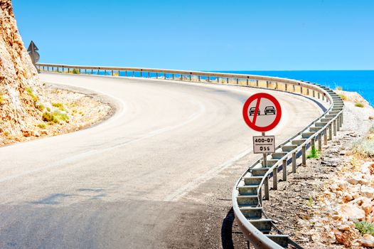 road sign and a mountain road along the sea