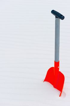 Vertical shot of an orange shovel in the sand