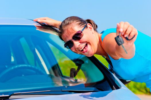 happy woman showing keys of her new car