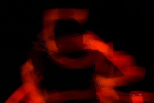Curved red lines that create a shadow person. Abstract forms of light in long exposure.