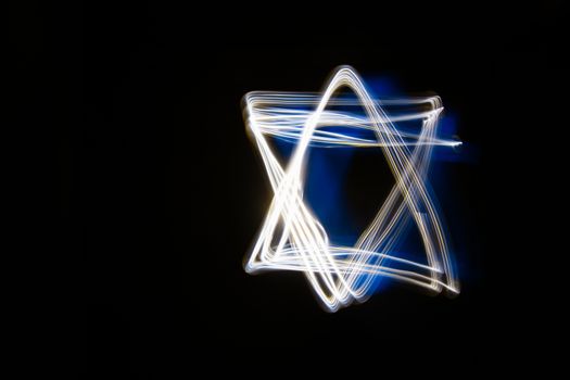 Blue and white Shield of David shape light. Abstract forms of light in long exposure.
