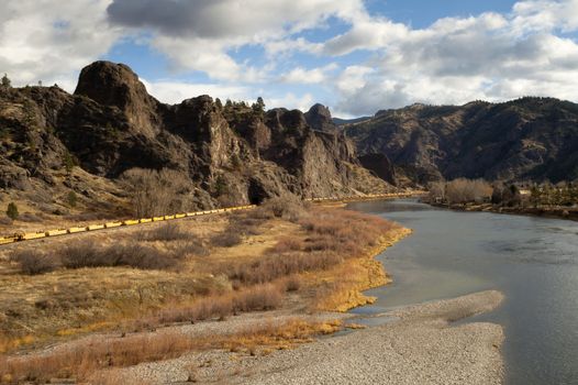 Yellow railcars sits in a low river bend in the Rocky Mountains