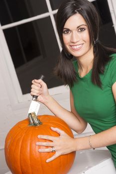 Pretty housewife cuts the top off a pumpkin getting it ready to carve