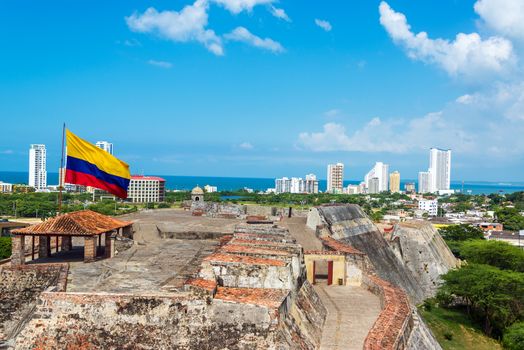 View of San Felipe de Barajas castle and the skyline of Cartagena, Colombia with a large Colombia flag