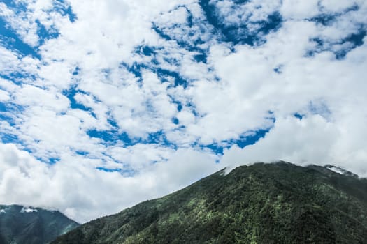 Scenic landscape with mountains, fields, forests, and clouds