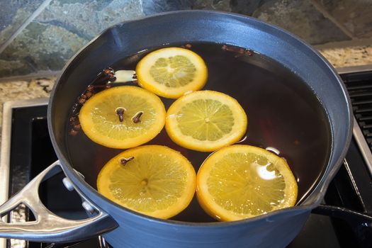 Hot Apple Cider with Orange Slices and Cloves Cooking in Kitchen Pot