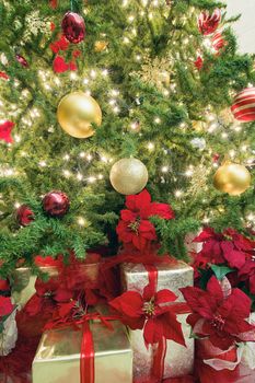 Christmas Tree Decoration with Lights Ornaments Ribbons Poinsettia and Presents Under the Tree