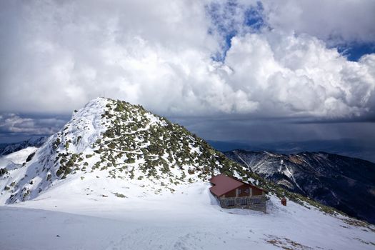 Mountain cabin in snowy mountains on cloudy day in cold winter