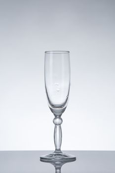 Empty champagne glass with natural reflection, studio shot on grey background 