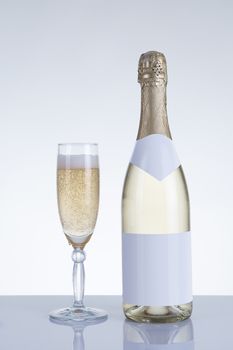 Champagne glass and a bottle with natural reflection, studio shot on grey background 