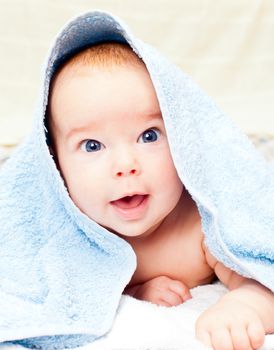 Little baby girl lying under blue towel