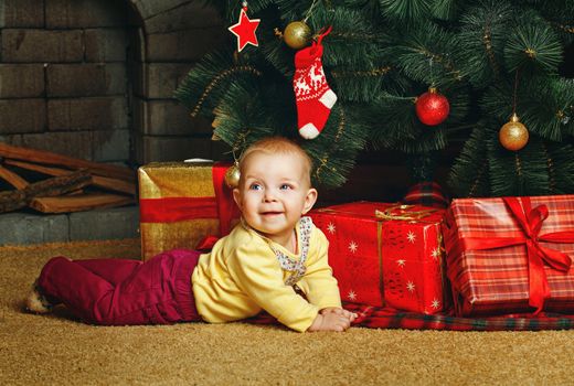 Redhead babe with blue eyes lies near the Christmas tree and gifts