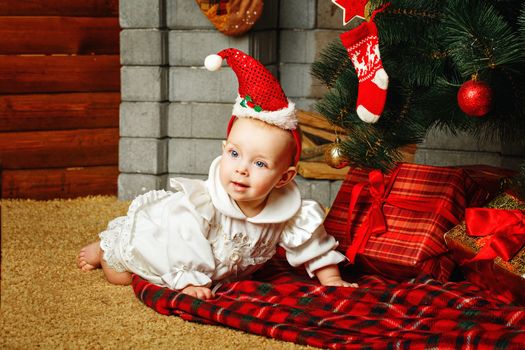 Redhead babe with blue eyes lies near the Christmas tree and gifts