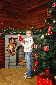 Boy shot on background with Christmas tree, gifts and fireplace