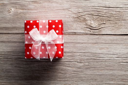 red gift box, polka dots, on wood background