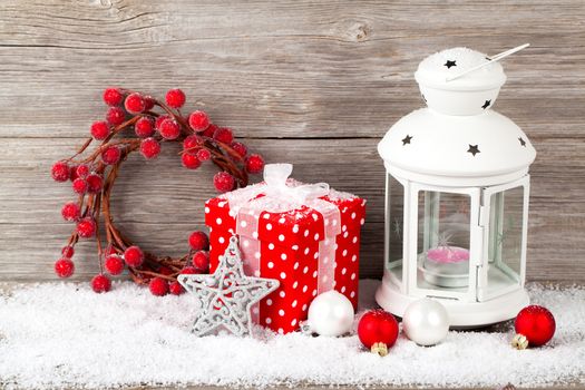 Burning lantern in the snow with christmas decoration, on wood background,