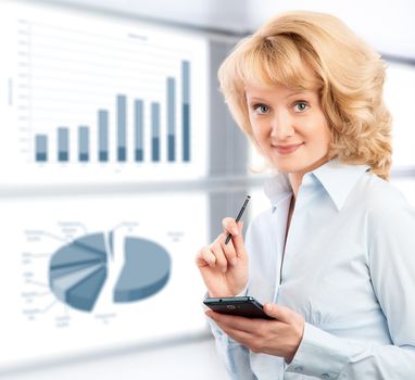 Business woman using her smartphone on the background graphics and charts