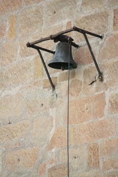 Old bell and rope hanging on a brick wall