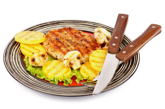 Roasted Turkey Steak Garnished with Grilled Sliced Potato, Portabello Mushrooms, Lettuce on Striped Plate with Fork and Knife isolated on white background