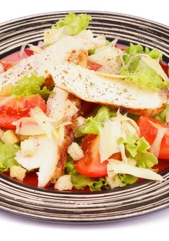 Traditional Caesar Salad with Grilled Chicken Breast, Garlic Crouton, Lettuce, Tomatoes and Grated Parmesan Cheese on Striped Plate closeup on white background