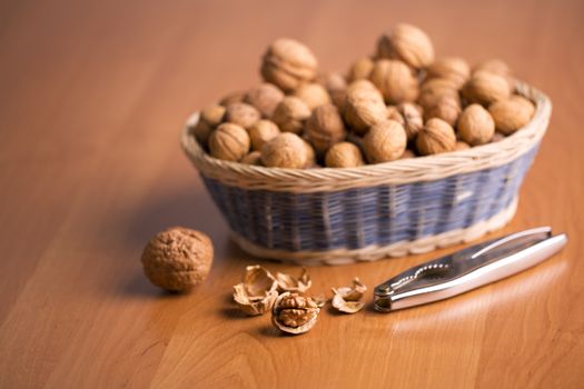 Nuts in a basket with the nutcracker, on a wooden background.