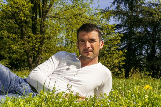 An attractive and cheerful man lying in the park