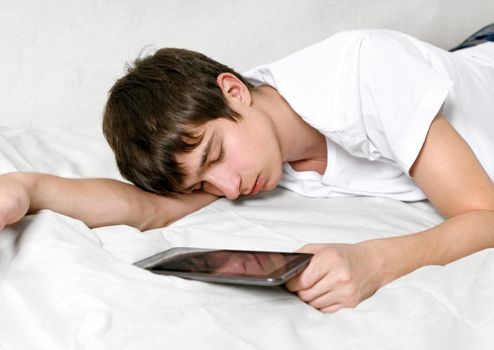 Tired Young Man Sleeps with Tablet Computer on the bed