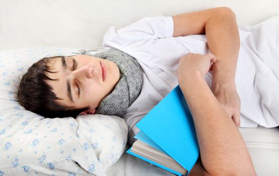 Tired Young Man Sleeps with a Book on the bed