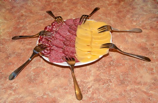 Plate with cheese and sausage in an environment of forks.