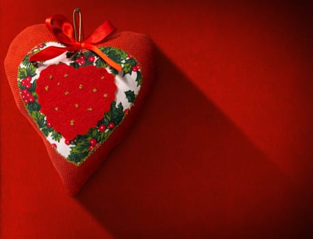 Christmas heart, red, white and green hanging on red velvet background with shadows