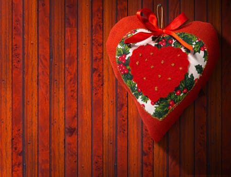 Christmas heart, red, white and green hanging on brown wooden wall with shadows